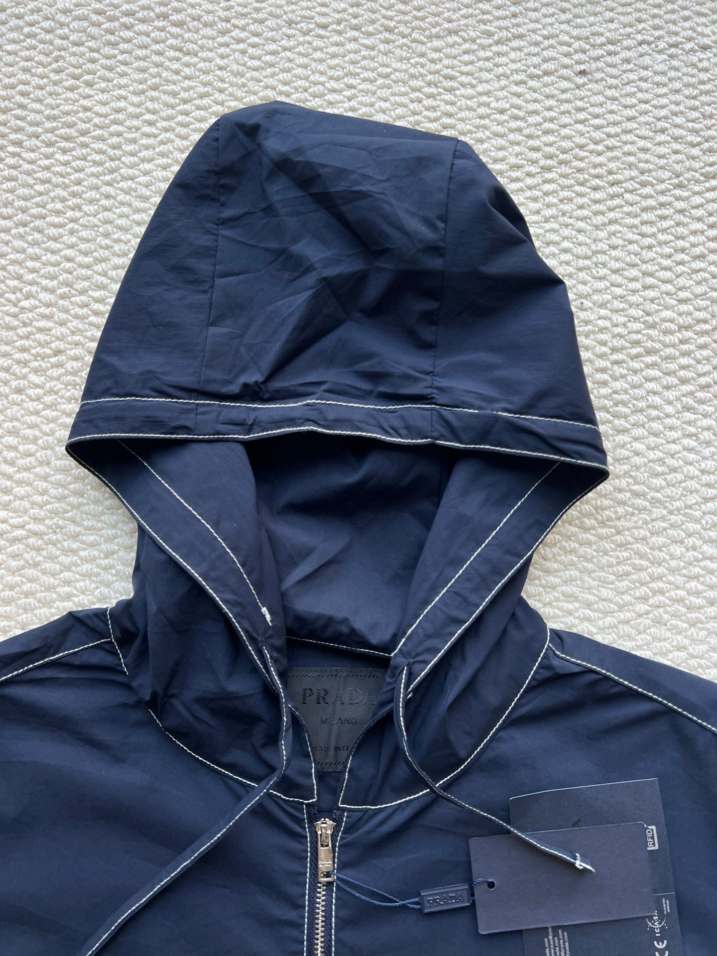 Men's navy hooded jacket with drawstring hood and front zipper close-up
