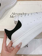 White leather sneaker with black heel accent and perforated lace-up panels