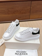 White leather sneakers with black heel inserts and lace-up front