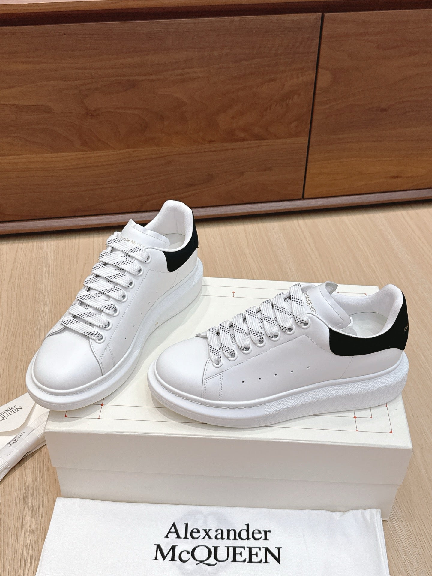 White leather sneakers with black heel inserts and lace-up front