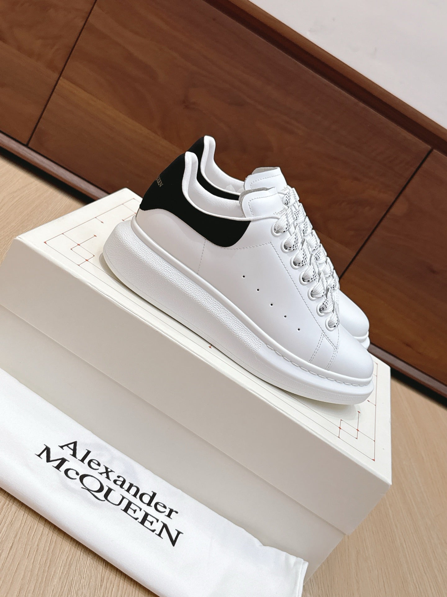 White leather low-top sneaker with black heel panel and perforated detailing