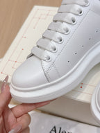 Alexander McQueen white leather sneakers, close-up of lace-up eyelets and side stitching