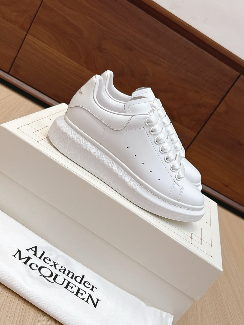 Alexander McQueen white leather sneakers, side angle with lace-up and perforated toe