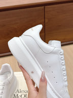 Alexander McQueen white leather sneakers, close-up side view with textured sole