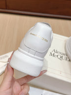 Alexander McQueen white leather sneakers, close-up of heel tab with embossed branding