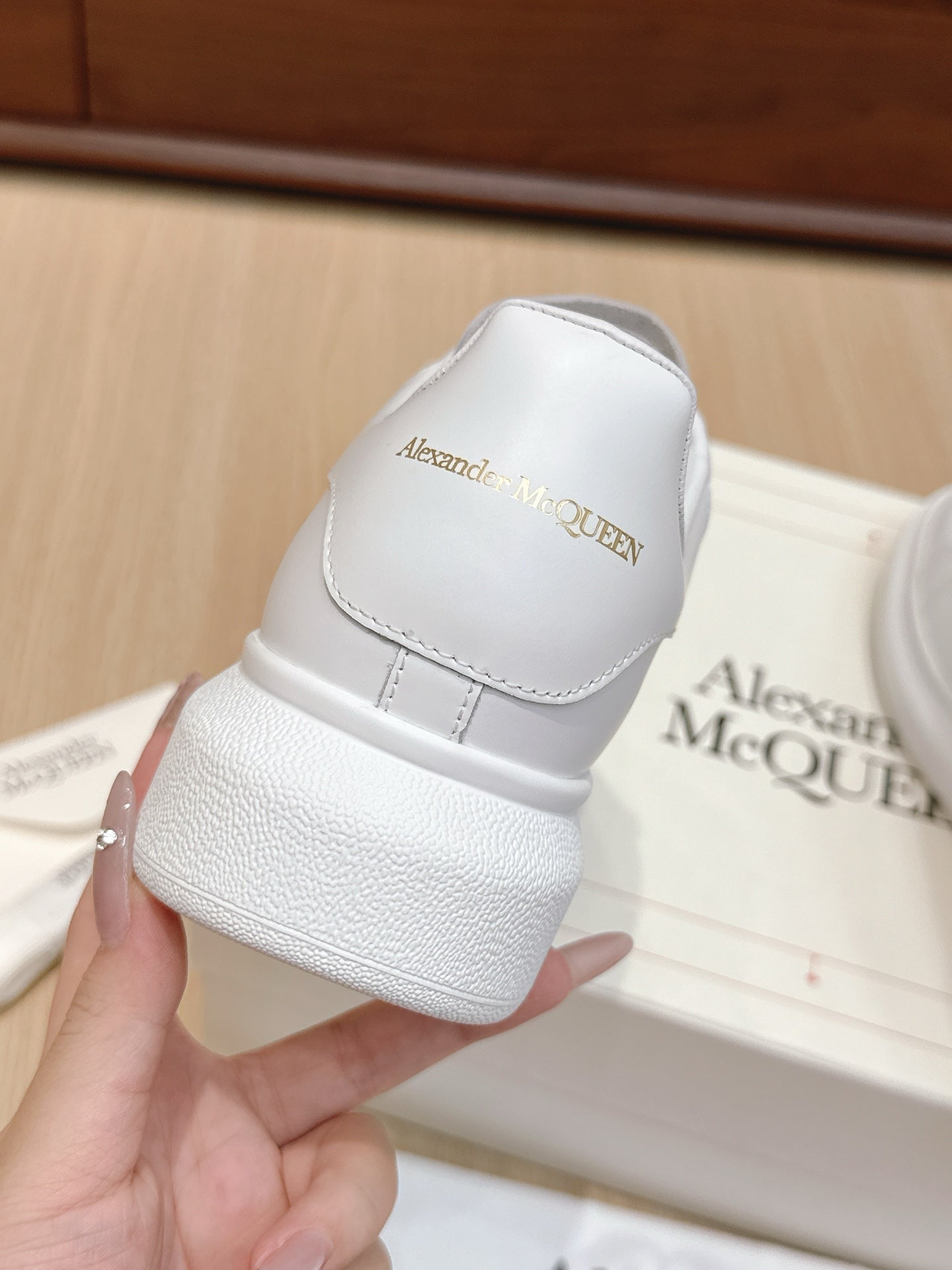 Alexander McQueen white leather sneakers, close-up of heel tab with embossed branding