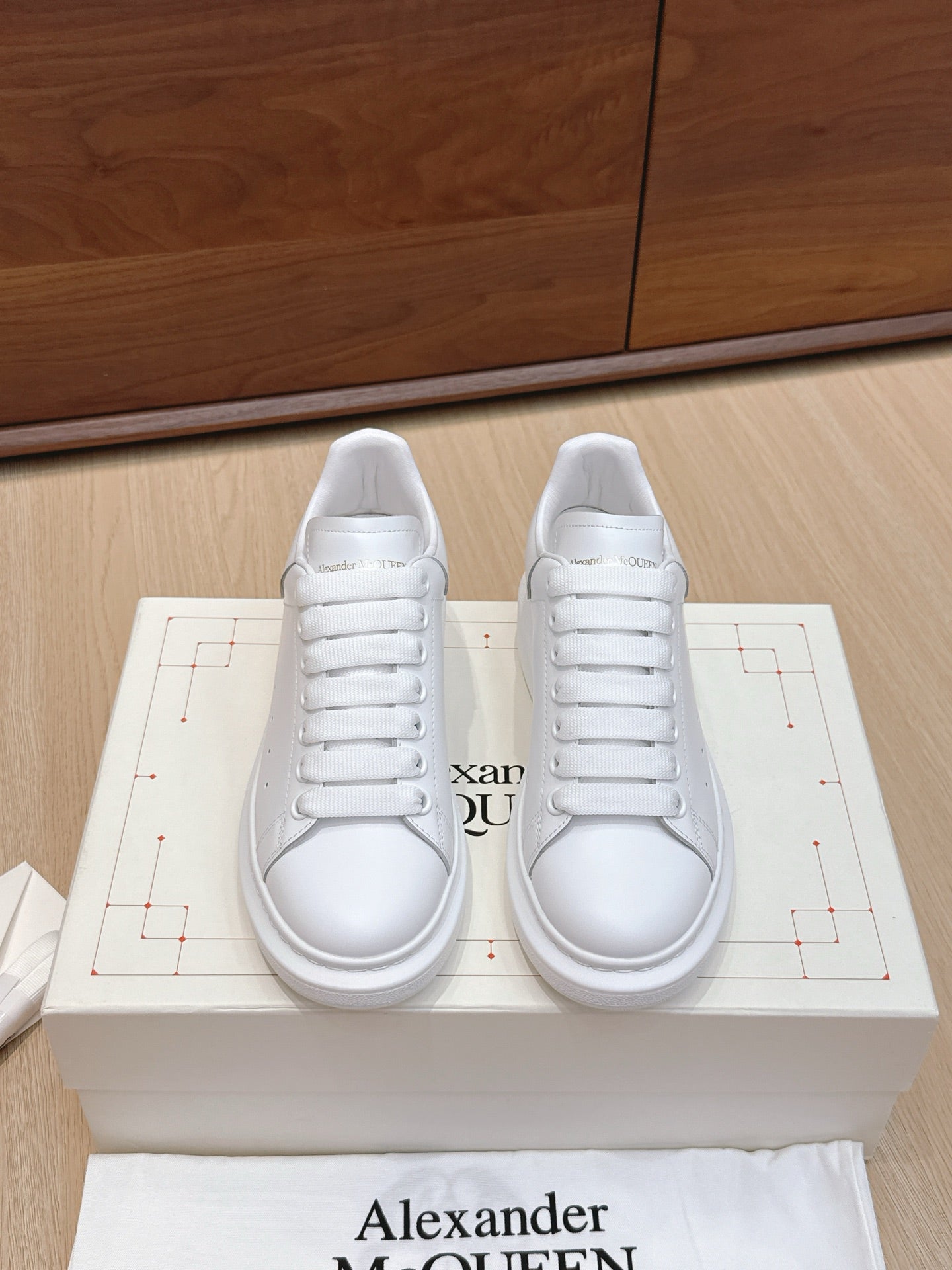 Alexander McQueen white leather sneakers, front view on box with lace-up design