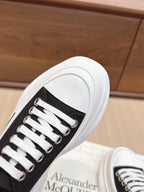 Black low-top sneakers with white lace-up front and metal eyelets