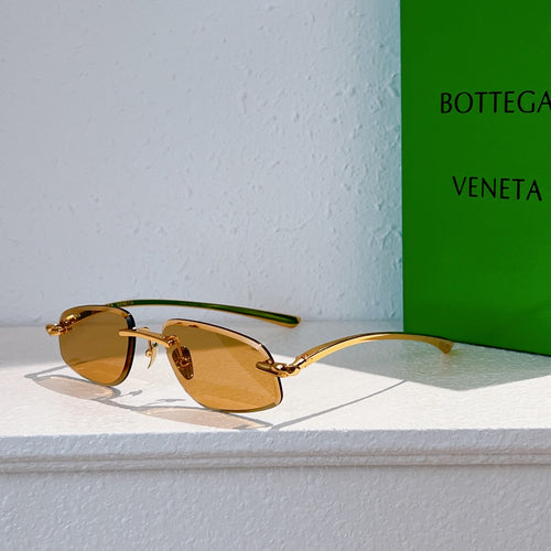 Bottega Veneta sunglasses with gold frame and amber tinted lenses, angled view