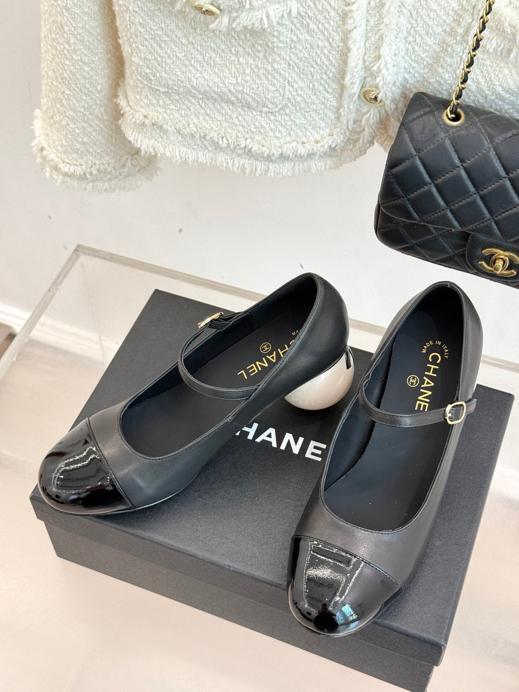 Black pumps with silver patent strap and buckle, shown on a dark box