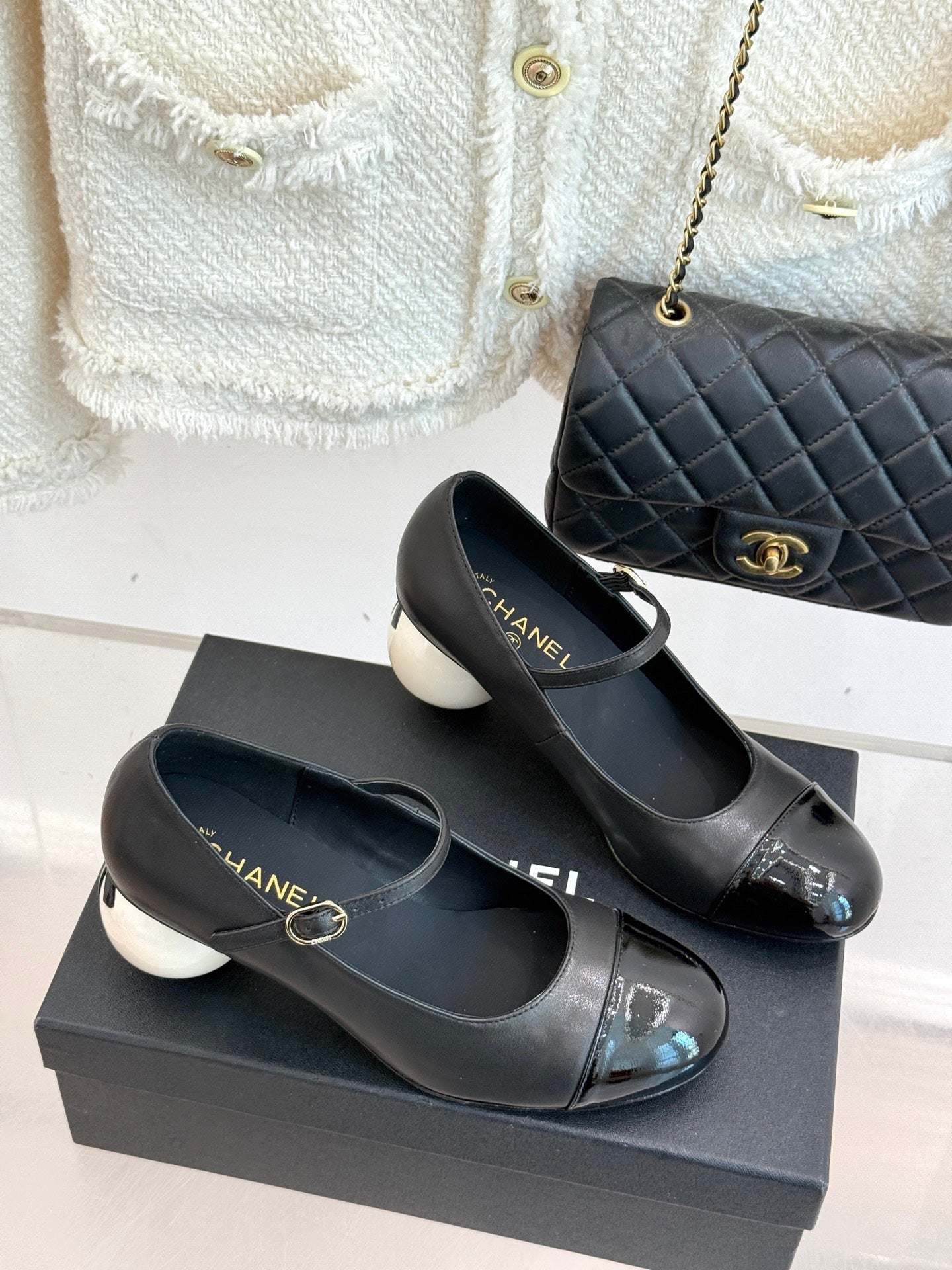 Black Mary Jane pumps with silver patent toe and round white heel on box