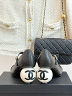 Pair of black pumps with round white heel caps and ankle strap