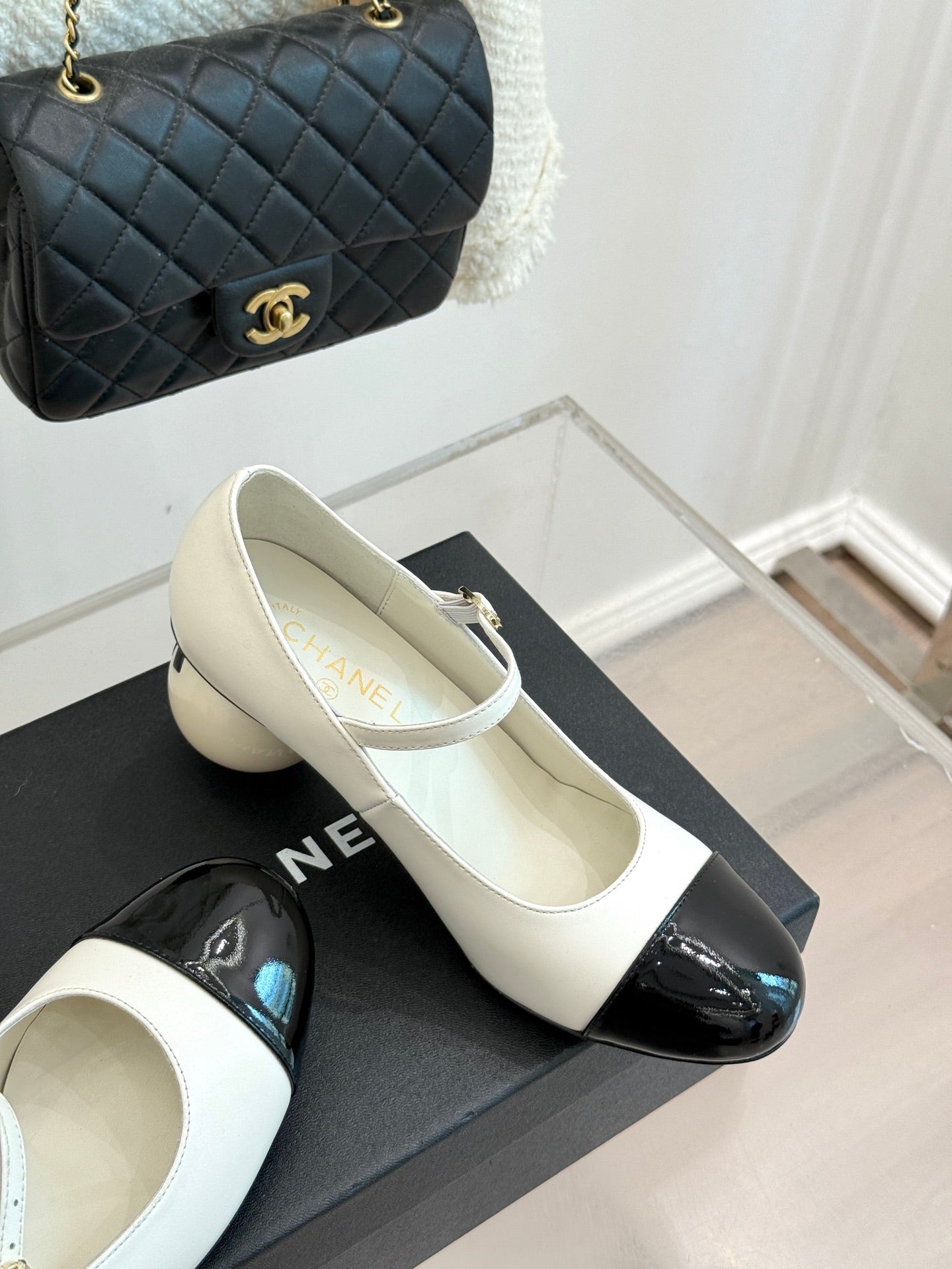Chanel women's flats pair, white uppers with black patent toe on a box