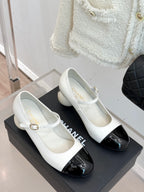 Chanel women's flats on a display box, white leather with black cap detail