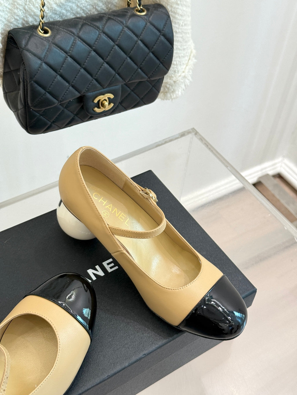 Beige Chanel flats with glossy black toe cap and small top bow strap detail