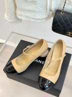 Beige Chanel flats with glossy black toe cap and small top bow ornament