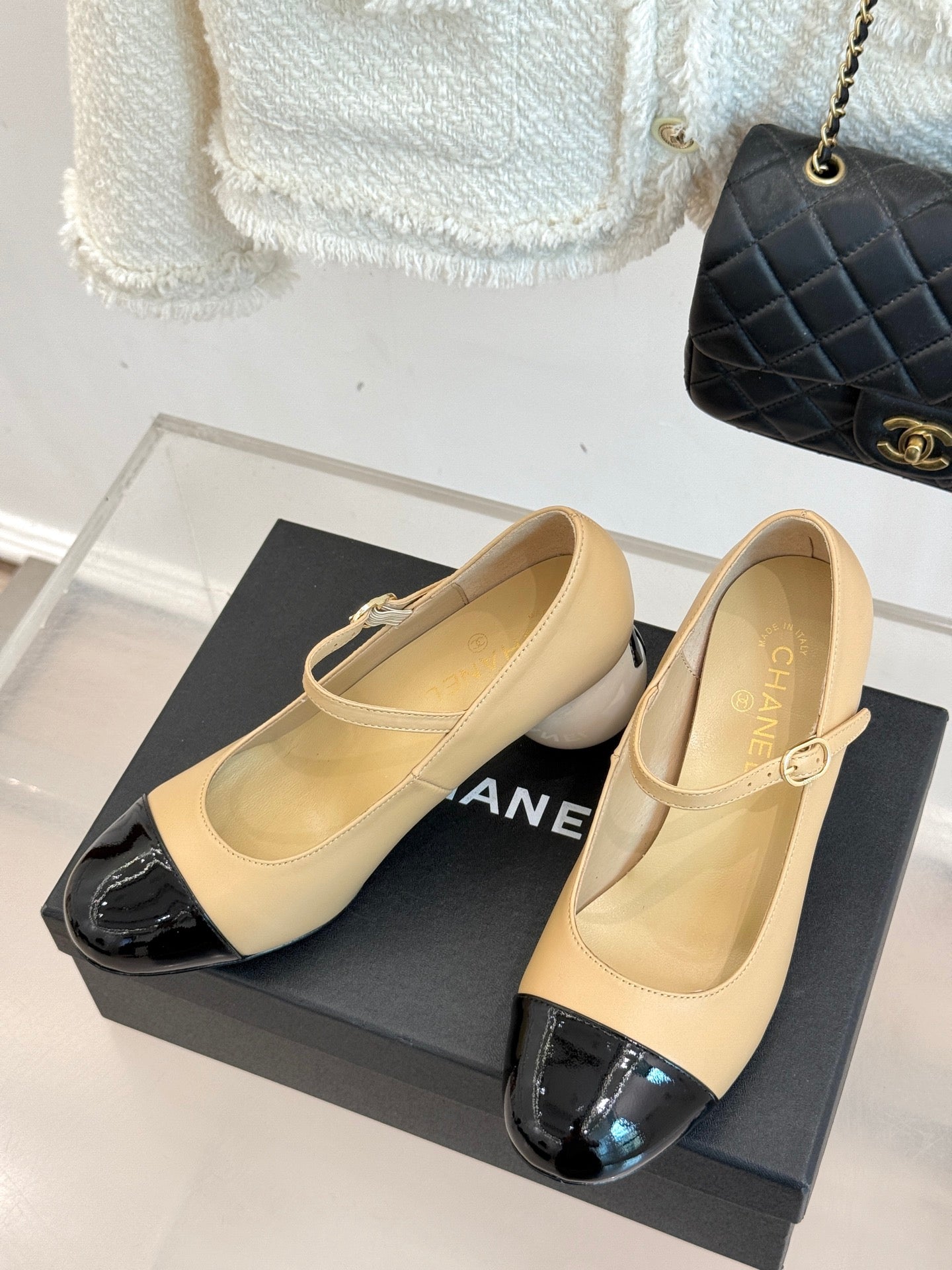 Beige Chanel flats with glossy black toe cap and small top bow ornament