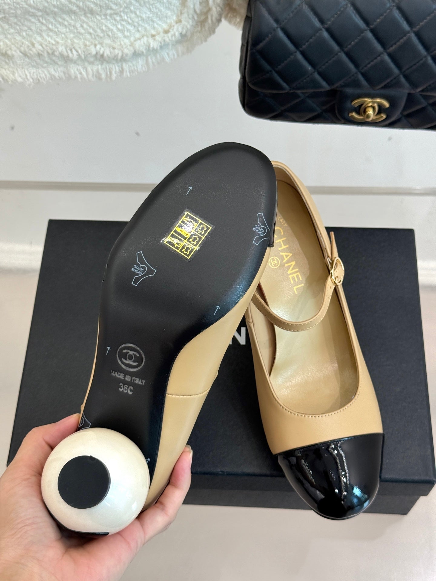 Beige Chanel flats with glossy black toe cap, shown with their branded box lid