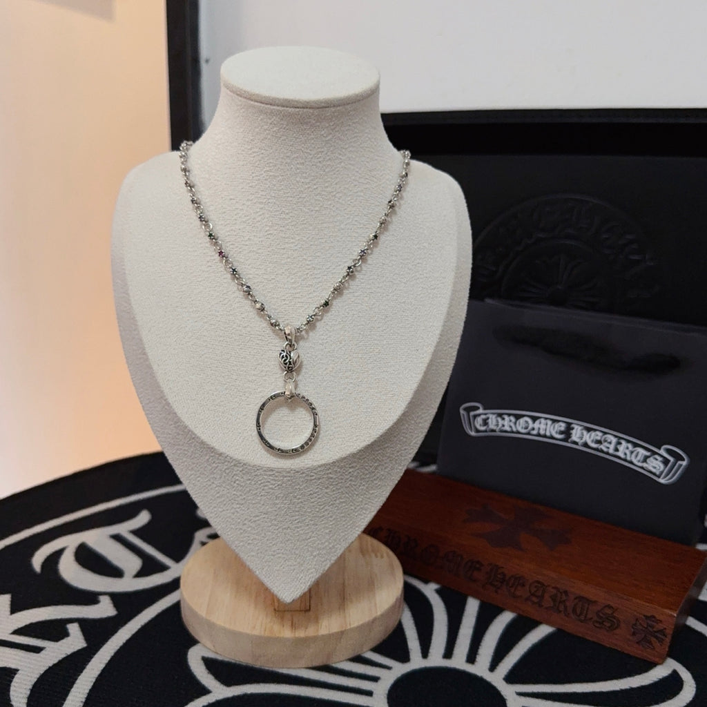Silver-tone chain necklace with round ring pendant on a display stand.