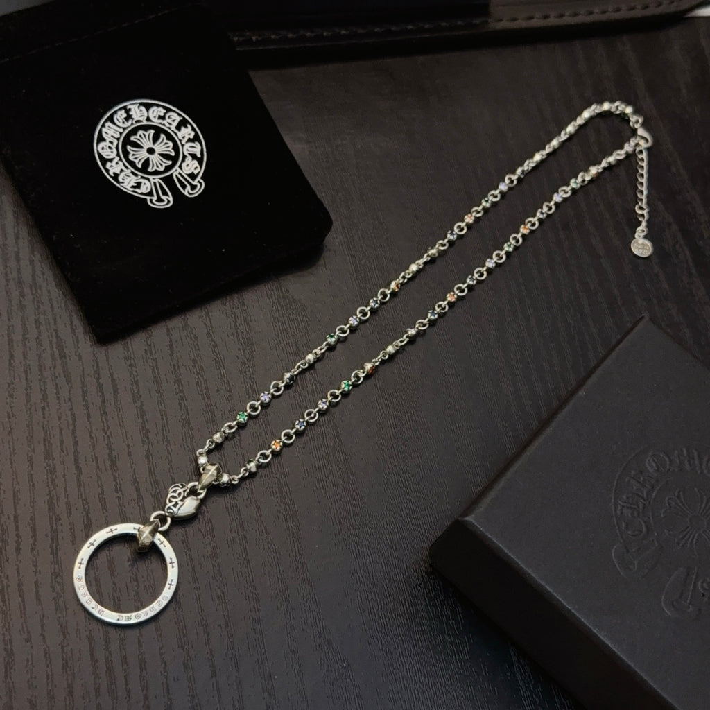 Silver-tone chain necklace with circular ring pendant next to folded jewelry box.