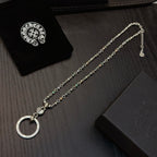 Silver-tone chain necklace with circular ring pendant next to folded jewelry box.