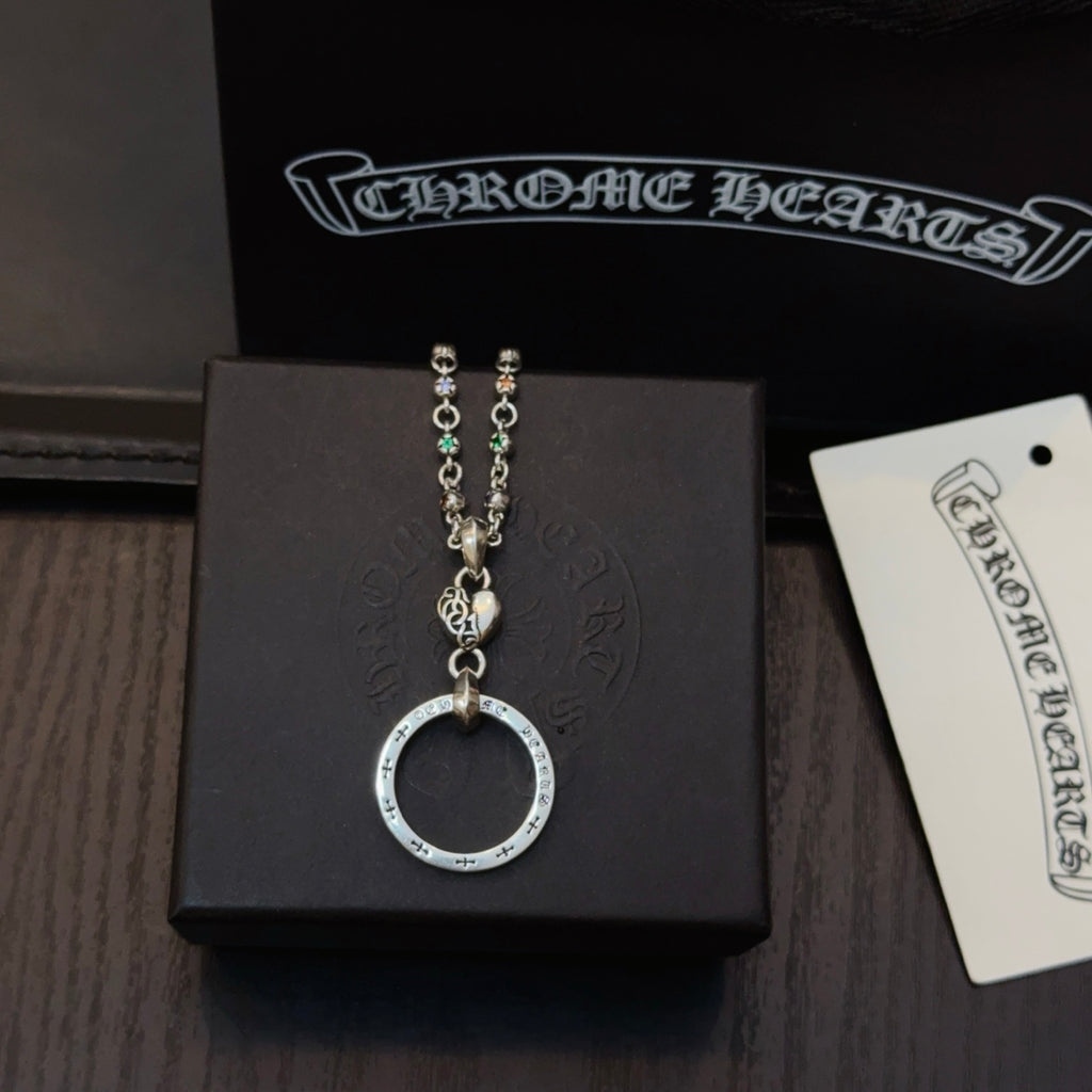 Silver-tone chain necklace with circular ring pendant on black box with tag.