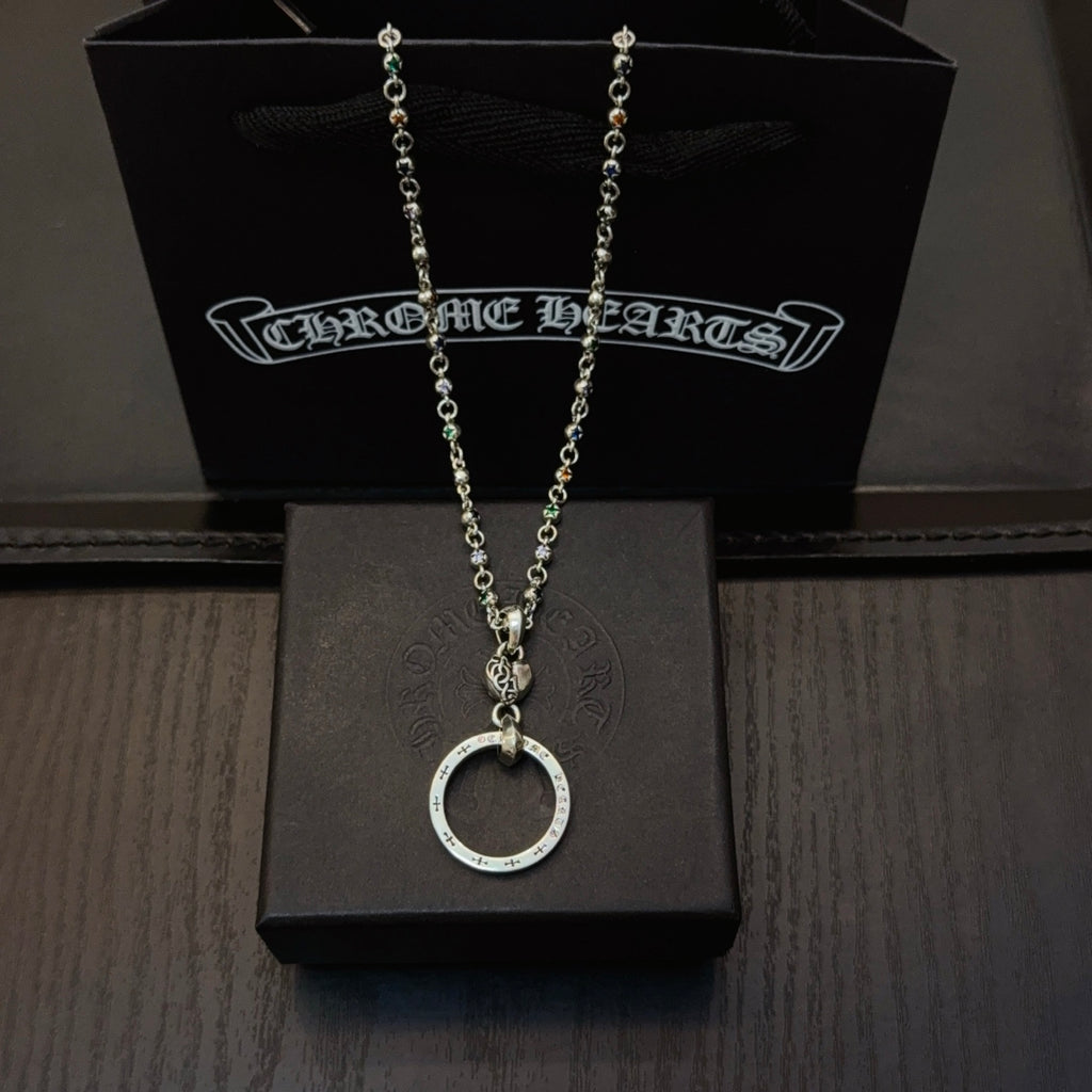Silver-tone chain necklace with circular ring pendant, displayed on a black jewelry box.