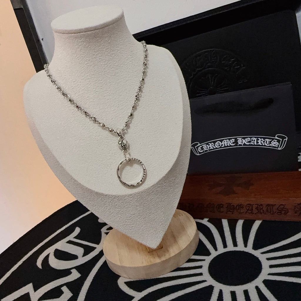 Silver-tone ring pendant necklace on a mannequin bust with chain and clasp detail.