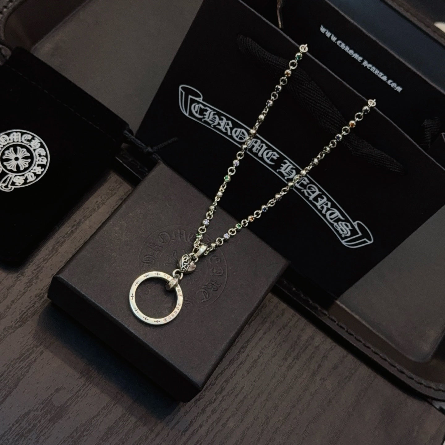 Silver-tone necklace with circular ring pendant laid on a dark jewelry display tray.