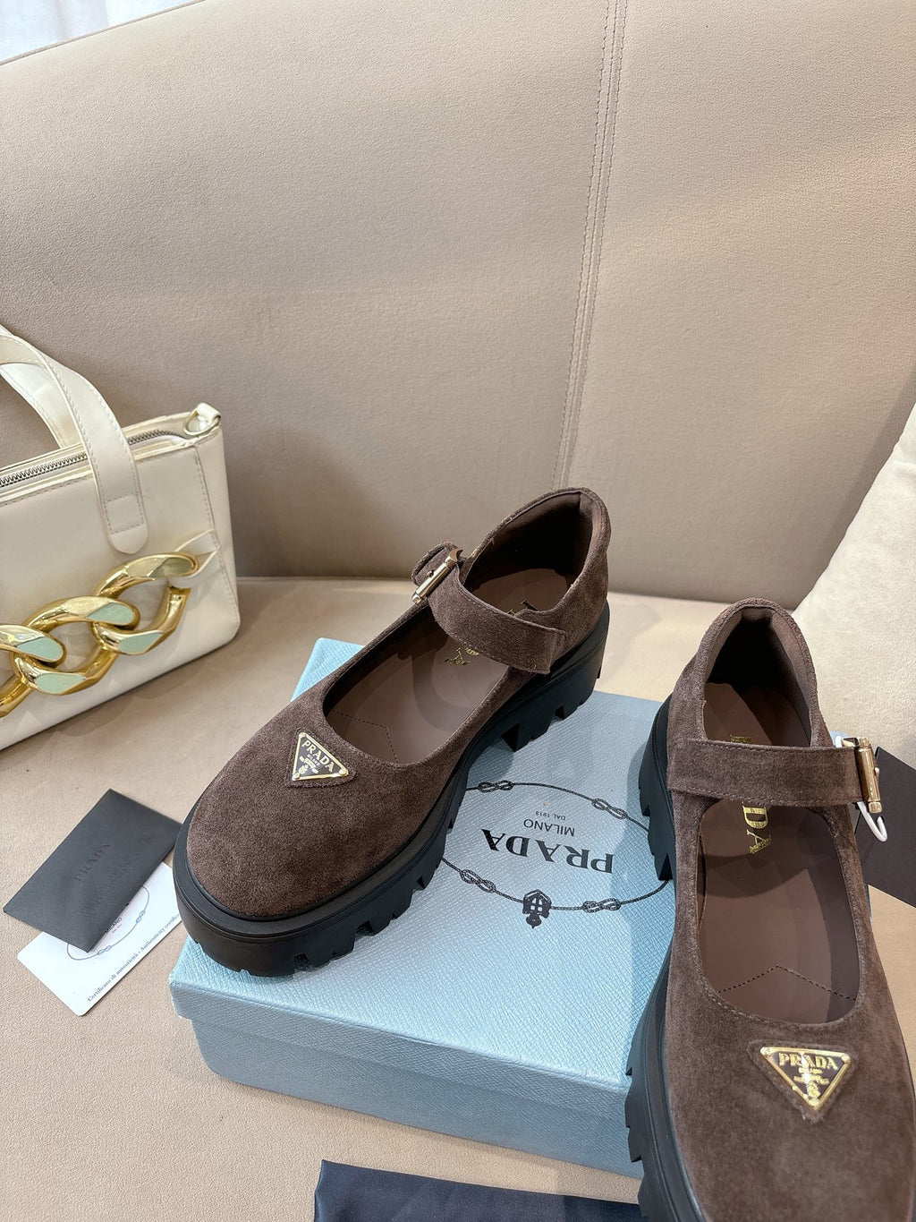 Prada women’s suede buckle shoes, brown, front view with triangular emblem.