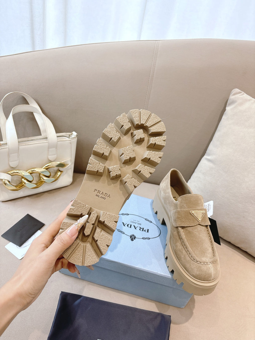 Beige suede loafer mules with strap; visible tread outsole, Prada