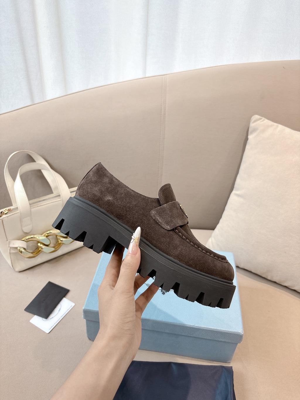Dark brown suede loafers with thick lug sole, slip-on strap with logo plaque