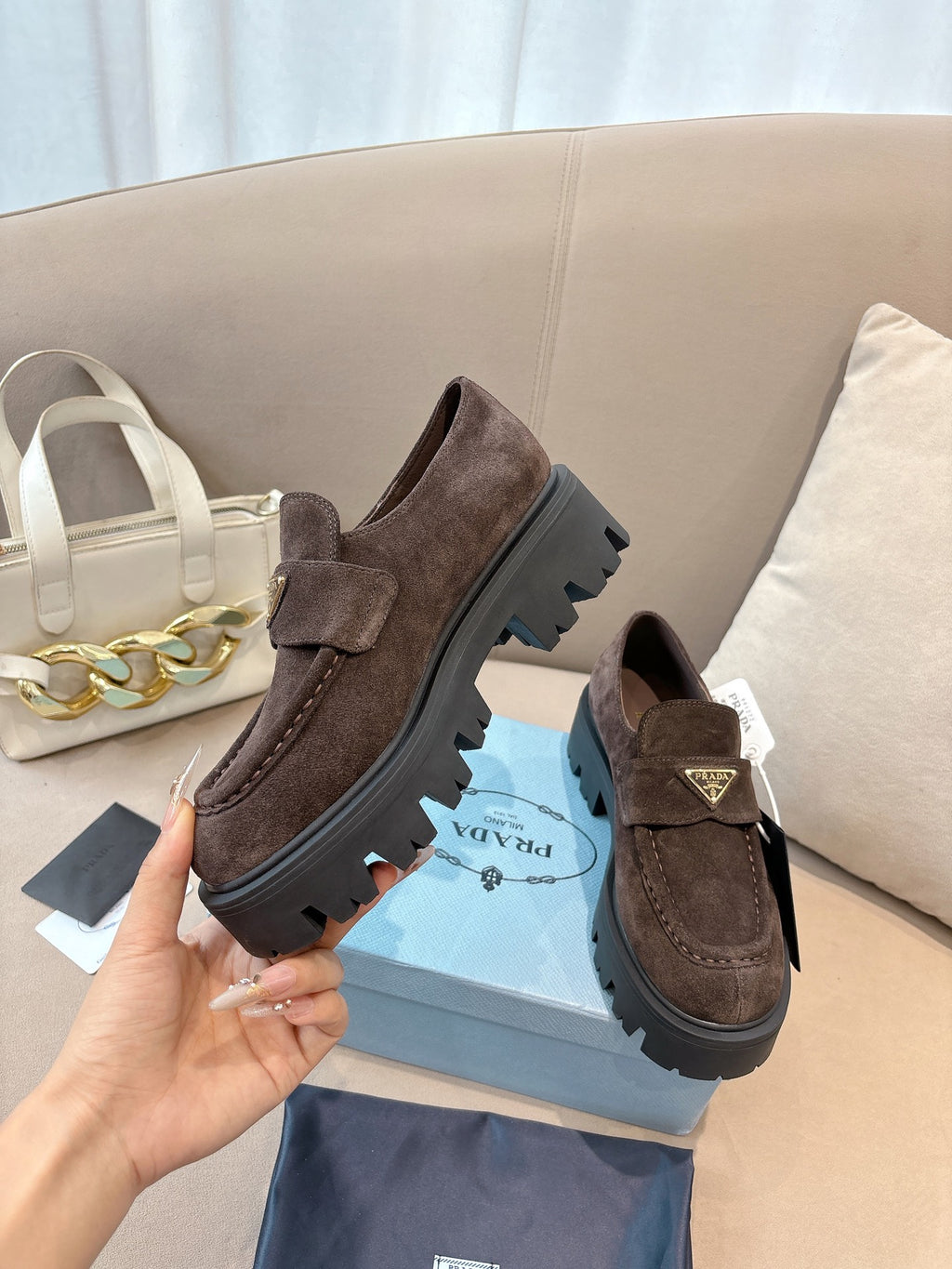 Dark brown suede loafers on blue box, chunky lug outsole and strap with logo