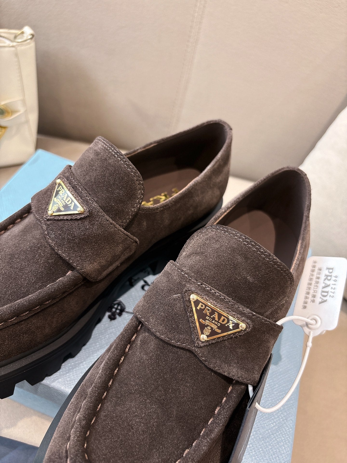Dark brown suede loafers with square logo plaques and chunky tread sole