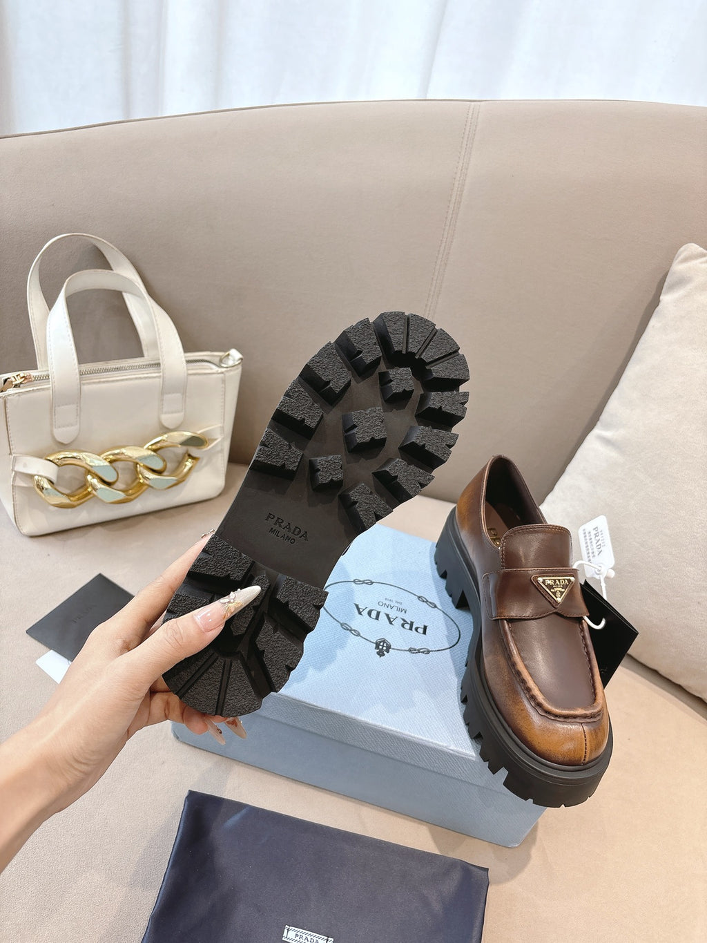 Prada ladies brown leather loafers with black rubber outsole tread and logo strap detail