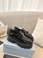 Prada ladies black patent loafers featuring front buckle and chunky treaded sole