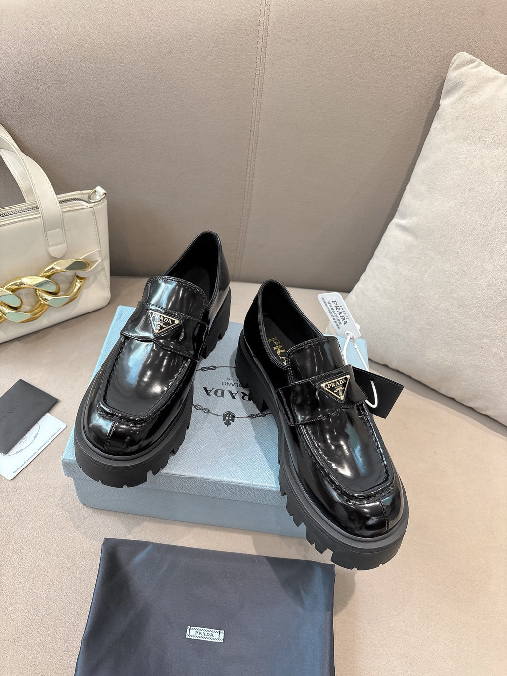 Prada ladies black patent loafers on display, with buckle strap and thick lug sole