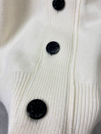 Cream knit cardigan front with black button detail and textured ribbed placket