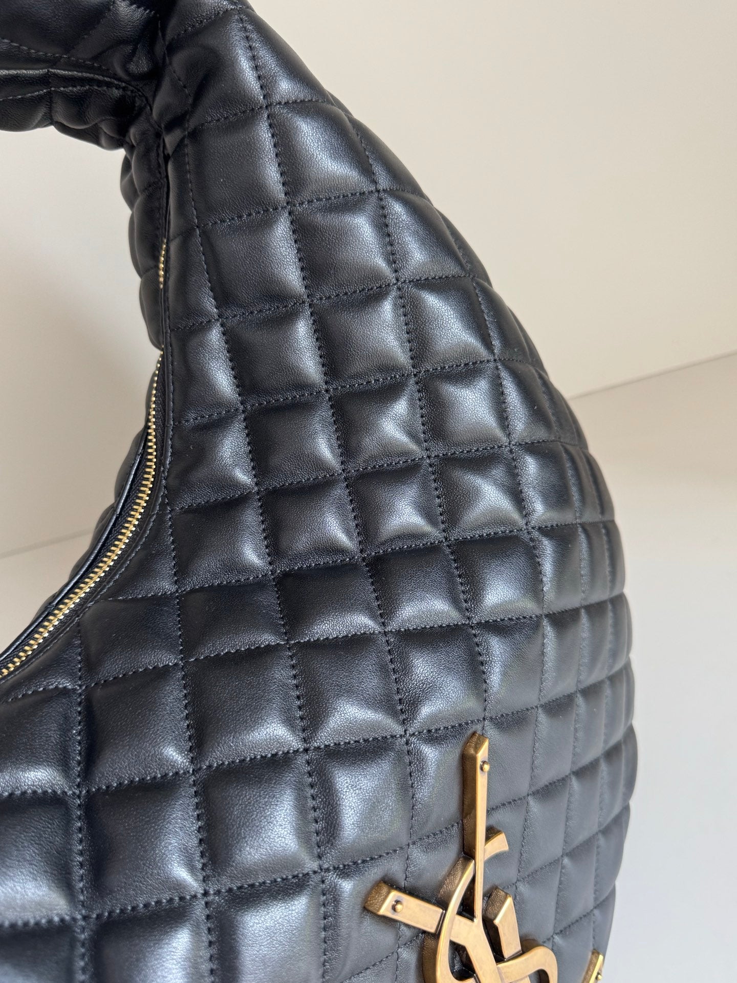 YSL quilted bag side close-up with gold zipper pull and hardware, dark