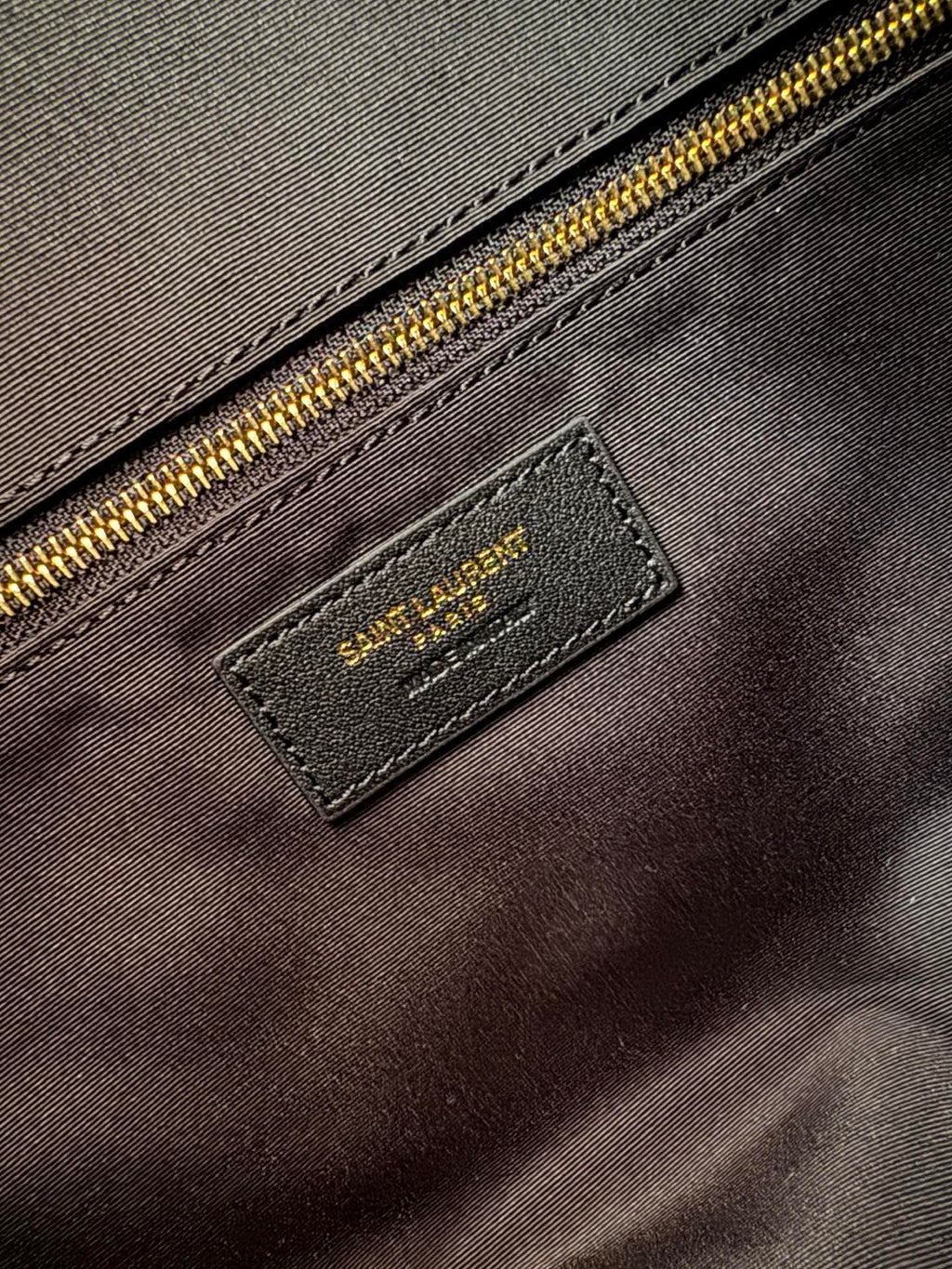 YSL logo label patch with gold zipper on dark quilted bag lining