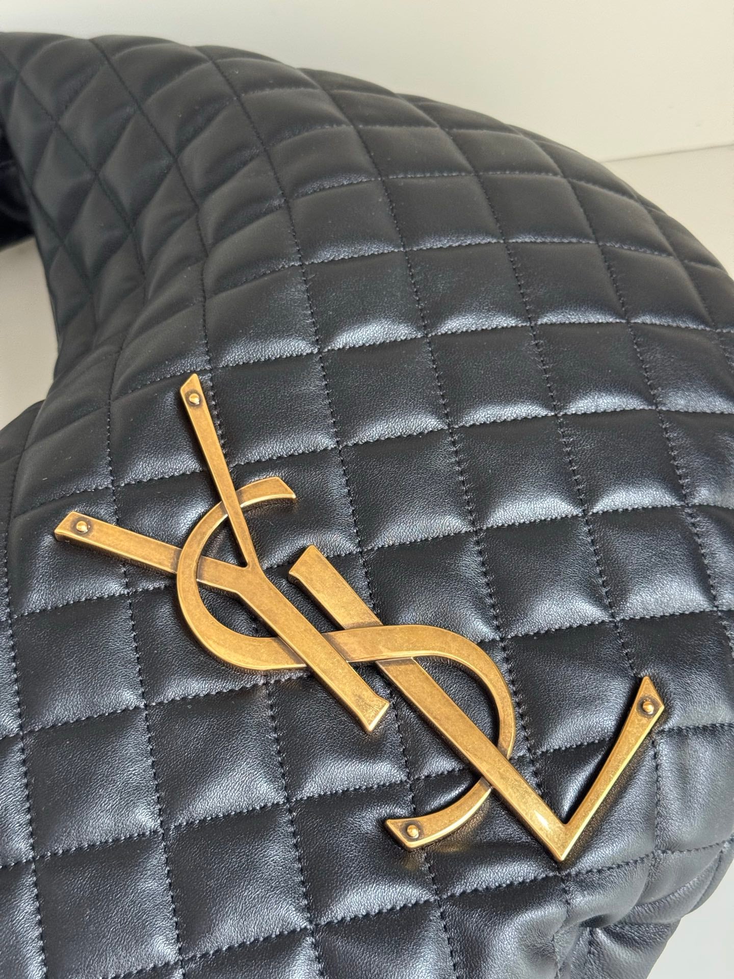 YSL quilted bag front close-up with gold YSL logo on dark leather-look