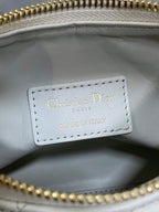 Dior label inside white quilted bag, stitched text with gold zipper edge.