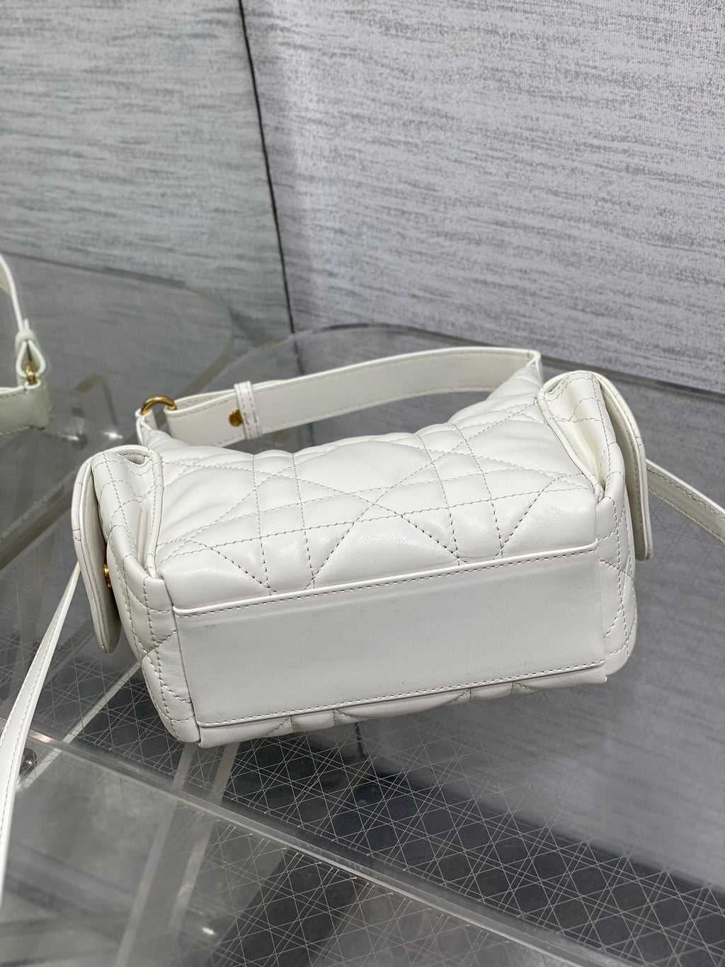 White Dior quilted shoulder bag with wide flap, top handle, and crossbody strap, side view.