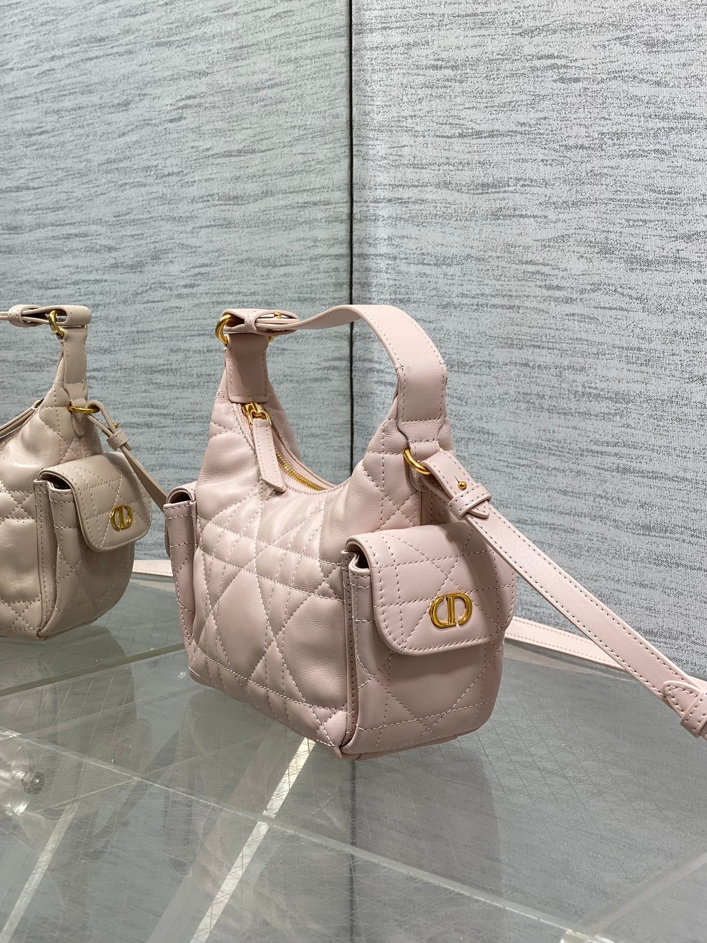 Dior quilted light pink bag on angled view with top handles, crossbody strap, and gold detail
