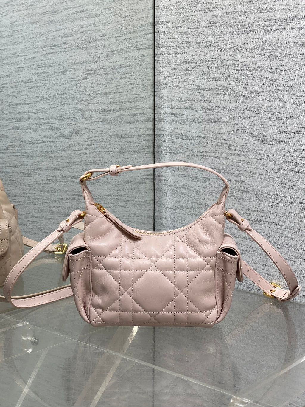 Dior quilted light pink hobo bag with two top handles, side gussets, and gold trim