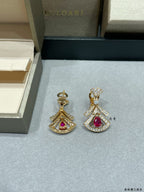Pair of dangling drop earrings with red teardrop gemstone and gold pavé settings.