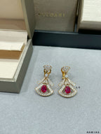 Pair of dangling drop earrings with gold setting and red gemstone centers, stud tops.