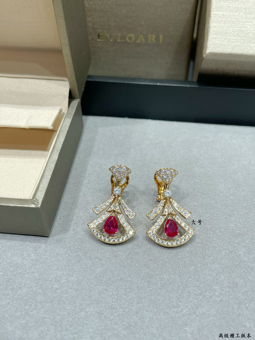 Pair of dangling drop earrings with gold setting and red gemstone centers, stud tops.