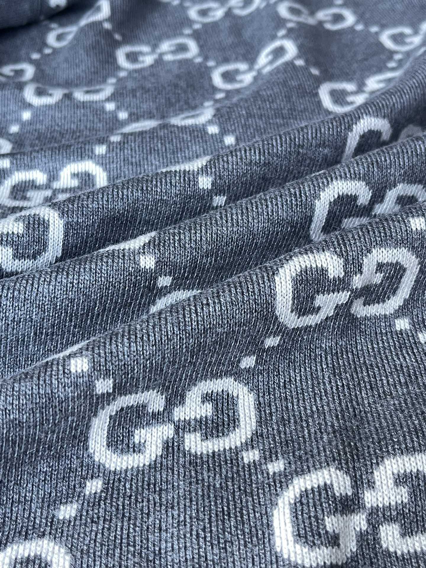 Close-up of Gucci GG logo pattern knit on dark gray zip-up hoodie fabric