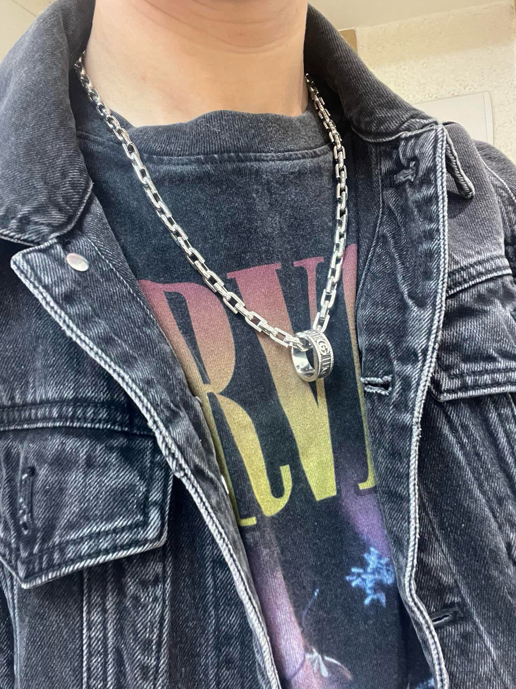 Silver-tone chain necklace with logo tag pendant on dark denim jacket